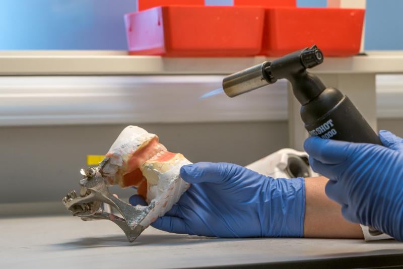 A denture being finished and detailed by hand